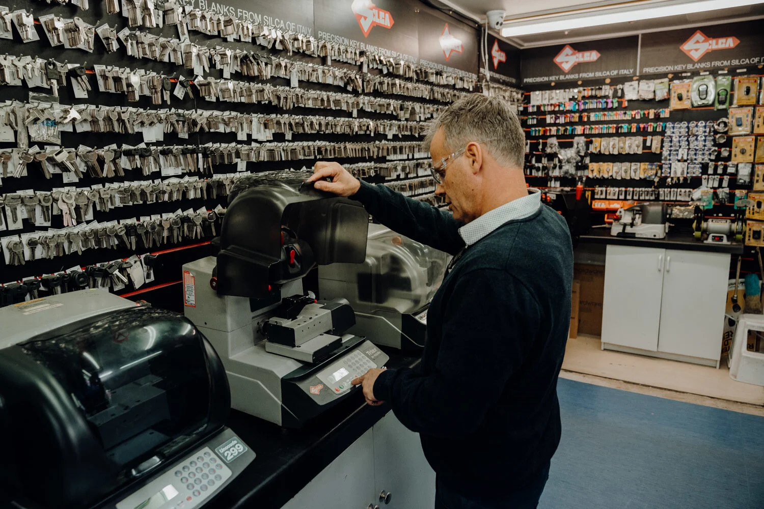 Auckland Locksmiths staff member cutting a key with a wall of keys in background